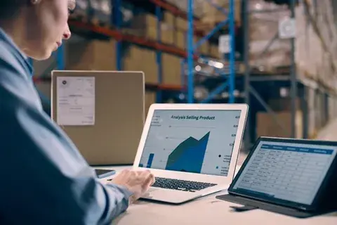woman working on laptop with data in warehouse