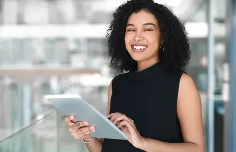 woman holding a tablet smiling in a warehouse
